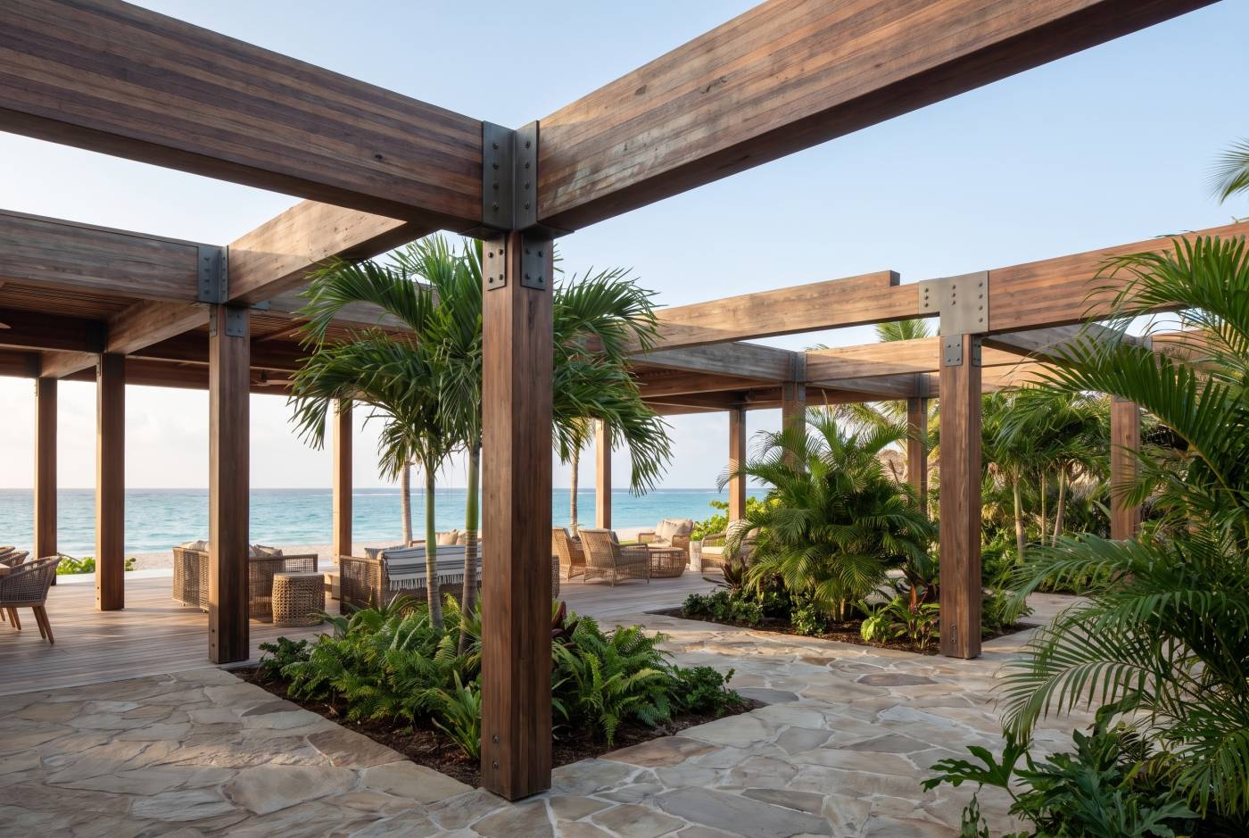 Hardwood glulam beams and posts with steel connections forming a covered pergola beside a tropical beach